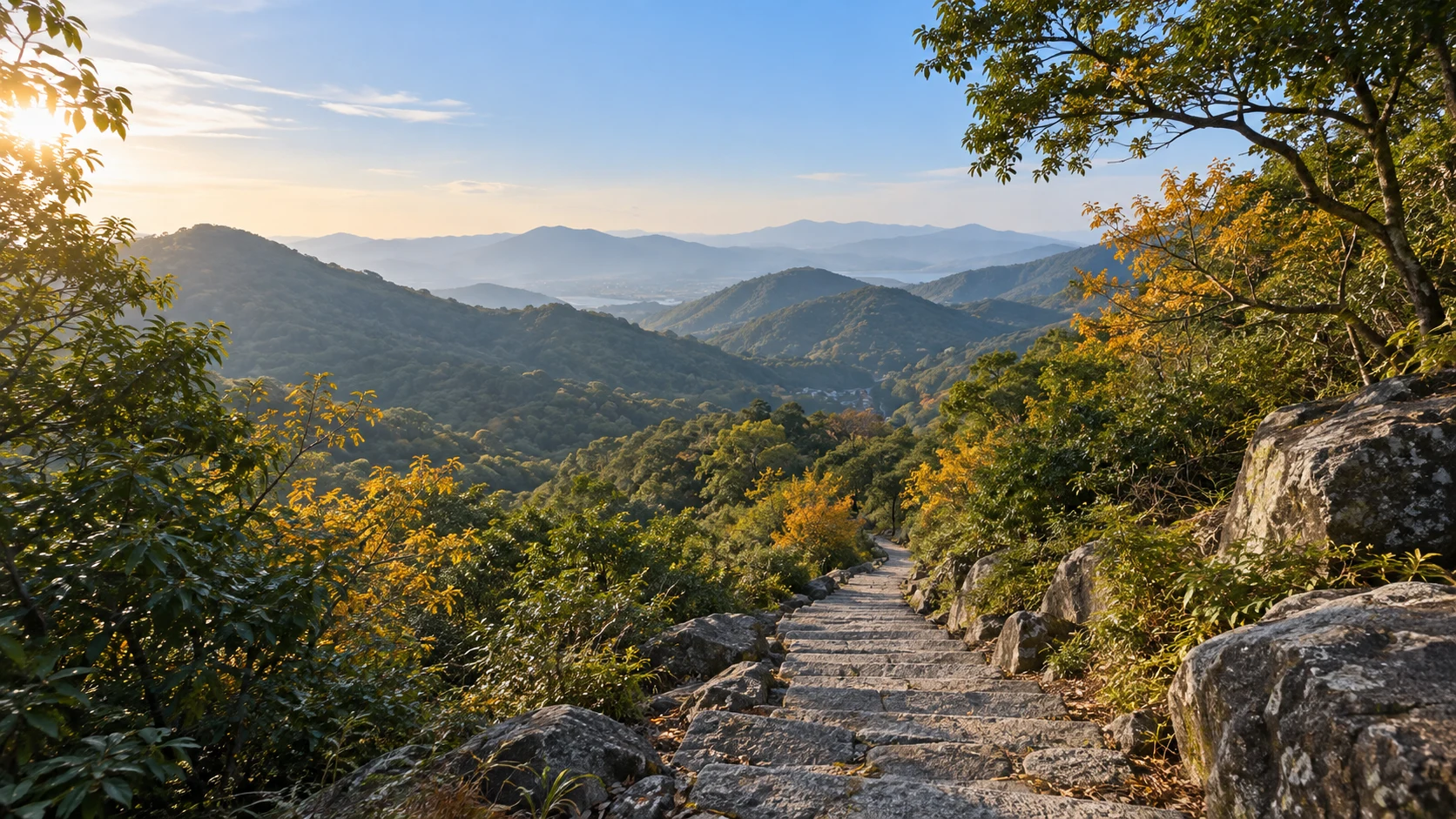 浙江宁波慈溪翠屏山丘陵十一月下旬,常绿树林夹杂少量金黄落叶,古朴的灰色石阶穿过林间从中央下方延伸,远处低山层叠,清朗柔和秋末阳光;不画雪峰或海滩